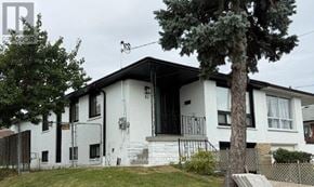 Toronto (Humbermede) apartment for rent - A white house with a black roof and a tree in front.