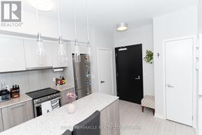 Toronto (Clanton Park) condo for rent - A modern kitchen with a black fridge and white cabinets.