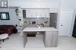 Toronto (Clanton Park) condo for rent - A modern kitchen with a central island and a refrigerator covered in magnets.