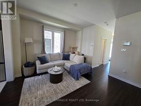 Brantford apartment for rent - A living room with a white couch and a grey rug.