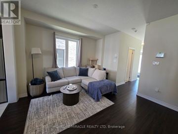 Brantford apartment for rent - A living room with a white couch and a grey rug.