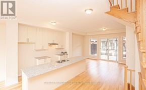 Oakville (Jm Joshua Meadows) townhouse for rent - A spacious kitchen with white cabinets and a wooden staircase.