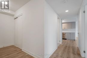 Pickering (Bay Ridges) condo for rent - A room with white walls and wooden flooring, with a door on the left and a window with blinds on the right.