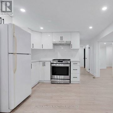 Thorold (Allanburg/Thorold South) apartment for rent - A white kitchen with a refrigerator, oven, and cabinets.