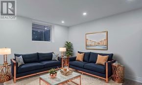 Thorold (Allanburg/Thorold South) apartment for rent - A living room with a dark blue sofa, a glass table, and a framed picture on the wall.