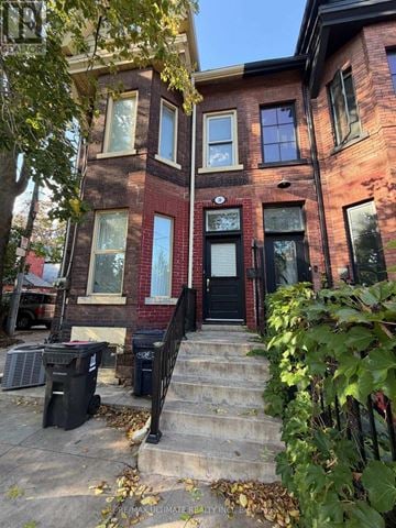 Toronto (Trinity-Bellwoods) apartment for rent - A red brick house with a black door and steps leading up to it.