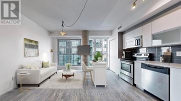 Toronto (Niagara) condo for rent - A modern kitchen with stainless steel appliances and a dining area with a white sofa and chairs.