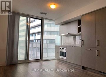 Toronto (Waterfront Communities) condo for rent - A modern kitchen with a sliding glass door leading to a balcony.