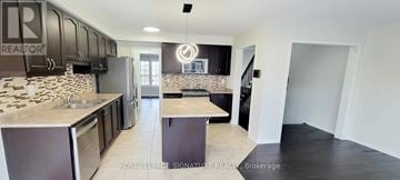 Pickering (Duffin Heights) townhouse for rent - A kitchen with black cabinets and a stone backsplash.