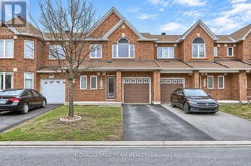Ottawa townhouse for rent - A large brick house with a tree in front and two cars parked in the driveway.