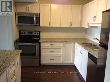 Guelph (Downtown) condo for rent - A kitchen with white cabinets and a granite countertop.
