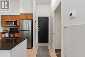 Toronto (Niagara) condo for rent - A kitchen with a refrigerator, microwave, and cabinets.