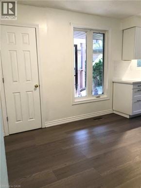 Hamilton apartment for rent - A room with a white door and a window with a view of a tree and a building outside.