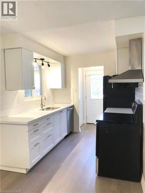 Hamilton apartment for rent - A modern kitchen with white cabinets and a black stove top oven.
