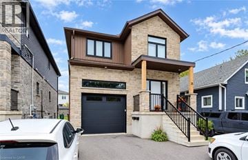 Kitchener apartment for rent - A modern house with a garage and a car parked in front.