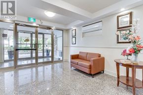 Vaughan (Islington Woods) condo for rent - A well-lit hallway with a brown leather couch and a wooden table with flowers on it.
