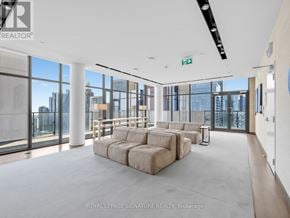 Toronto (Church-Yonge Corridor) condo for rent - A spacious living room with a large sectional sofa and a view of the city through the windows.