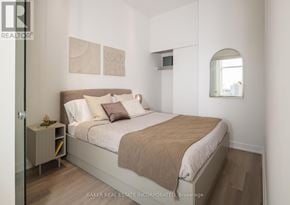 Toronto (Waterfront Communities) condo for rent - A bedroom with a bed, nightstand, and a window.
