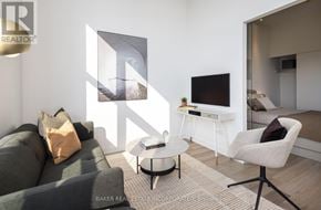 Toronto (Waterfront Communities) condo for rent - A living room with a grey couch, a white desk, and a television.