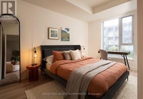 Toronto (Waterfront Communities) condo for rent - A bedroom with a large bed and a view of a cityscape through the window.
