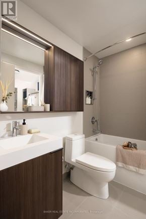 Toronto (Waterfront Communities) condo for rent - A modern bathroom with a white toilet and a brown cabinet.
