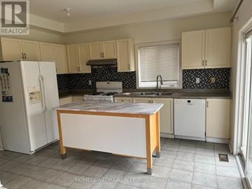 Vaughan (Vellore Village) apartment for rent - A kitchen with a white fridge, a wooden island, and a black and white backsplash.