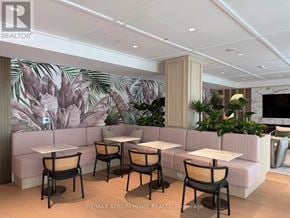 Vaughan (Vaughan Corporate Centre) condo for rent - A modern dining area with a large mural of leaves on the wall.