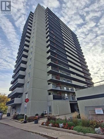 Ottawa condo for rent - A tall building with a sign that says "SOLID ROCK REALTY Brokerage" in front of it.
