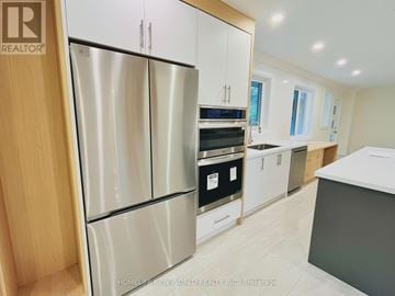 Toronto (St. Andrew-Windfields) apartment for rent - A modern kitchen with a stainless steel refrigerator and wooden cabinets.