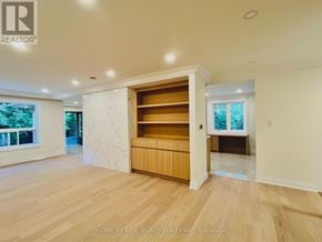 Toronto (St. Andrew-Windfields) apartment for rent - A spacious room with wooden flooring and a built-in shelf unit.