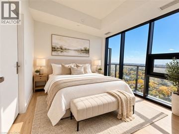Kitchener condo for rent - A bedroom with two beds and a large window overlooking a cityscape.
