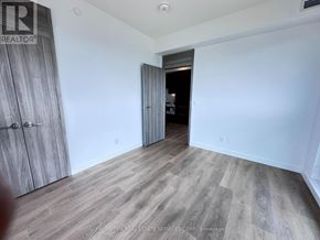 Toronto (Bayview Village) condo for rent - A room with a wooden floor and a white wall with a doorway leading to another room.