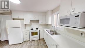 Ottawa townhouse for rent - A white kitchen with a refrigerator, oven, sink, and microwave.