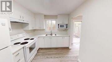 Ottawa townhouse for rent - A white kitchen with a stove top oven and a microwave above the sink.