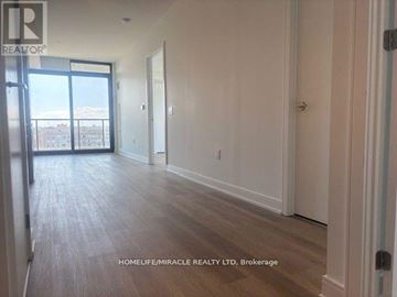Mississauga (Cooksville) condo for rent - A spacious room with wooden flooring and a view of the city through the sliding glass door.