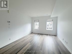 Oshawa (Windfields) townhouse for rent - A room with wooden flooring and two windows.