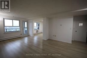 Waterloo condo for rent - A spacious room with wooden floors and white walls, part of a property managed by Master's Trust Realty Inc.
