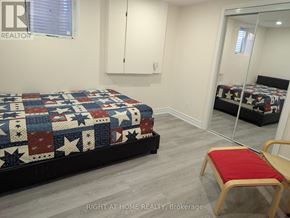 Ajax (Central West) apartment for rent - A bedroom with a bed covered in a quilt and a red chair.