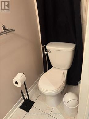 Mississauga (Lisgar) apartment for rent - A white toilet with a roll of toilet paper and a black plunger on the floor.
