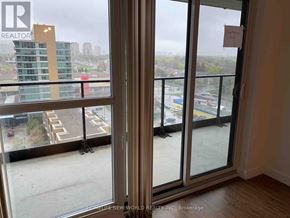 Toronto (Bayview Village) condo for rent - A room with a view of a parking lot and buildings through a sliding glass door.