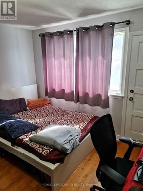Toronto (Woburn) apartment for rent - A bedroom with a bed, chair, and window with pink curtains.