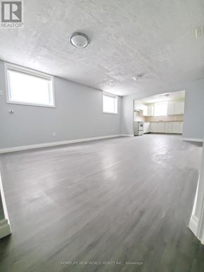 Barrie (Georgian Drive) apartment for rent - A spacious room with wooden flooring and white walls.