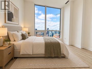 Toronto (Waterfront Communities) condo for rent - A bedroom with a large bed and a view of the city through the window.