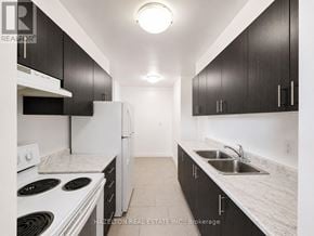 Toronto (Victoria Village) condo for rent - A kitchen with black cabinets and white appliances.