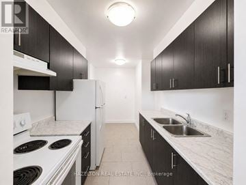 Toronto (Victoria Village) condo for rent - A kitchen with black cabinets and white appliances.