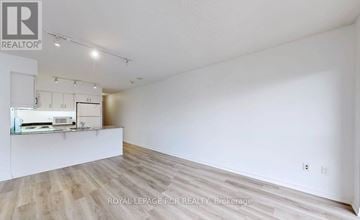 Toronto (Willowdale East) condo for rent - A spacious room with wooden flooring and white walls, featuring a kitchenette with a sink and cabinets.