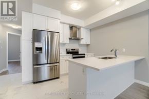 Kitchener townhouse for rent - A modern kitchen with a stainless steel refrigerator and white cabinets.