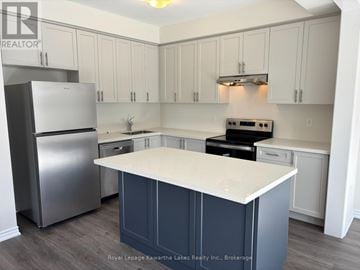 Kawartha Lakes (Lindsay) townhouse for rent - A kitchen with a refrigerator, stove, and cabinets.