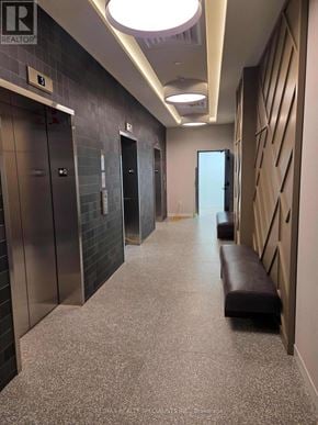 Mississauga (Central Erin Mills) condo for rent - A long hallway with a bench and elevators.