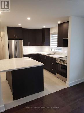 Vaughan (Maple) apartment for rent - A modern kitchen with dark brown cabinets and white countertops.